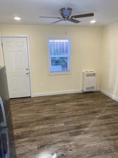A room with a ceiling fan and a window with blinds.