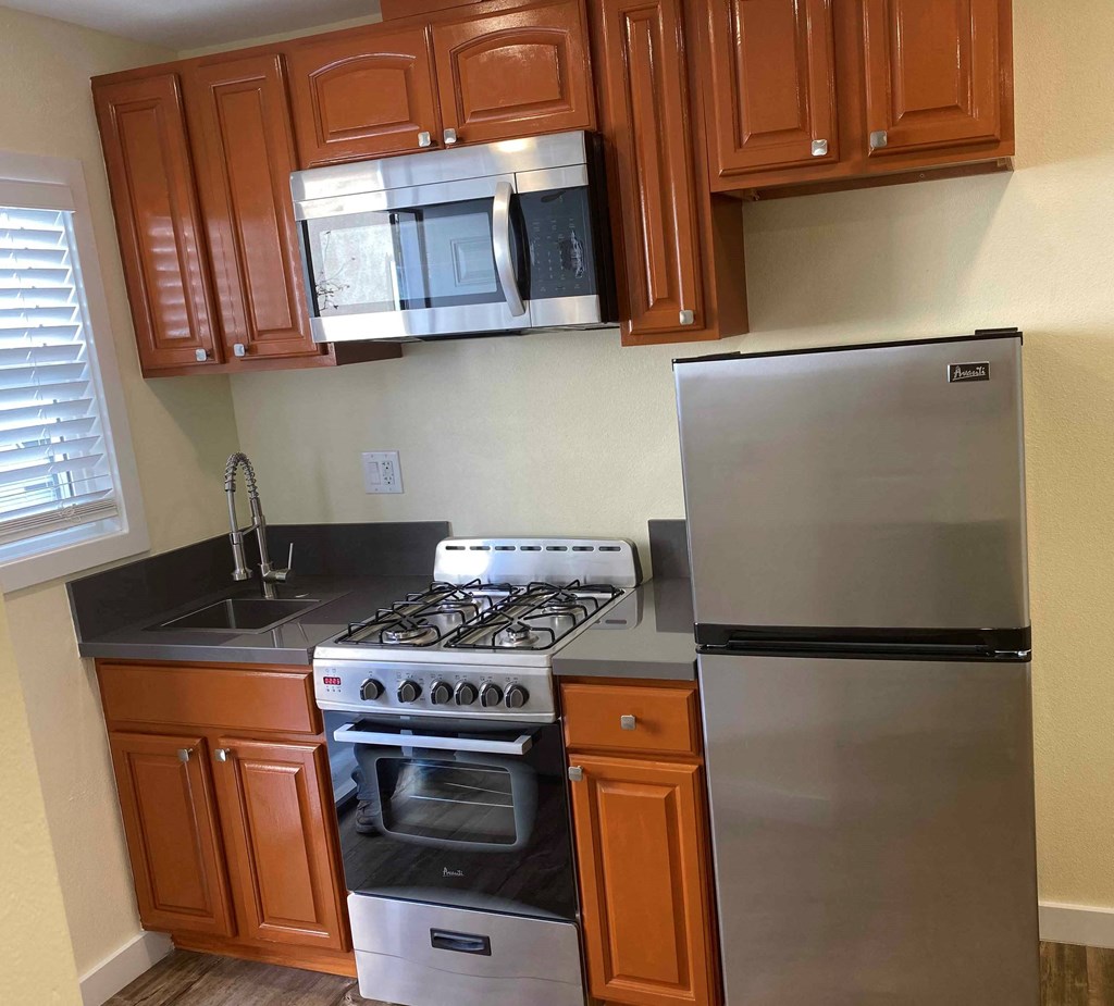 A kitchen with a stove, refrigerator, and cabinets.