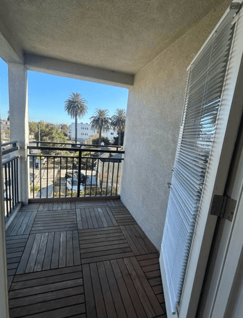 A balcony with a view of a street and palm trees.