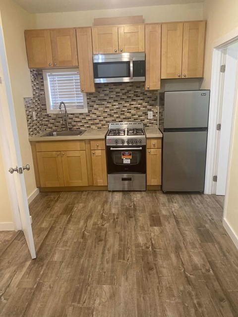 A kitchen with wooden cabinets and a black stove top oven.