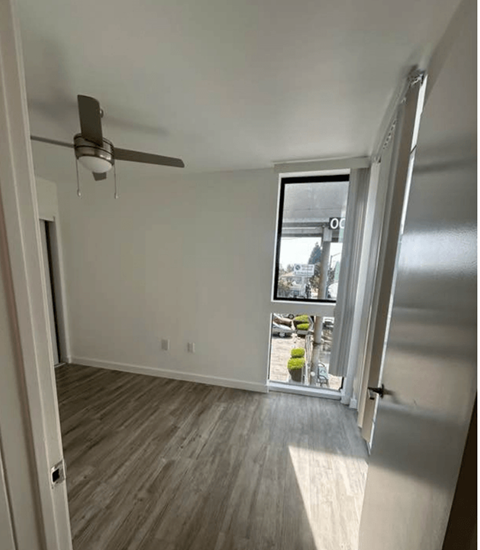 A room with a ceiling fan and a sliding glass door.