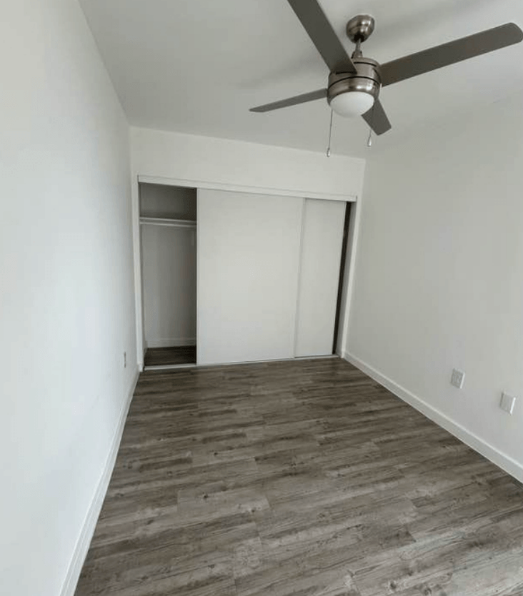 A room with a ceiling fan and wooden flooring.