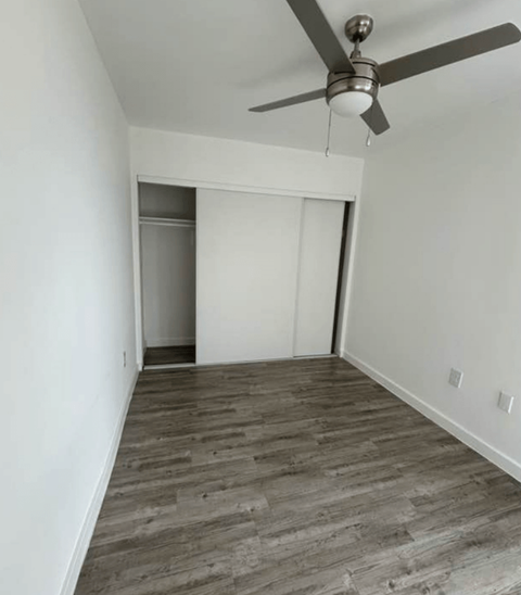 A room with a ceiling fan and wooden flooring.