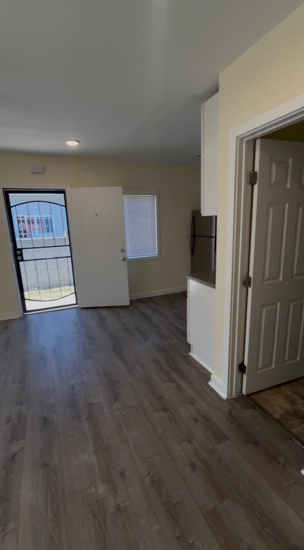 A room with a white door and a window with a view of a building outside.