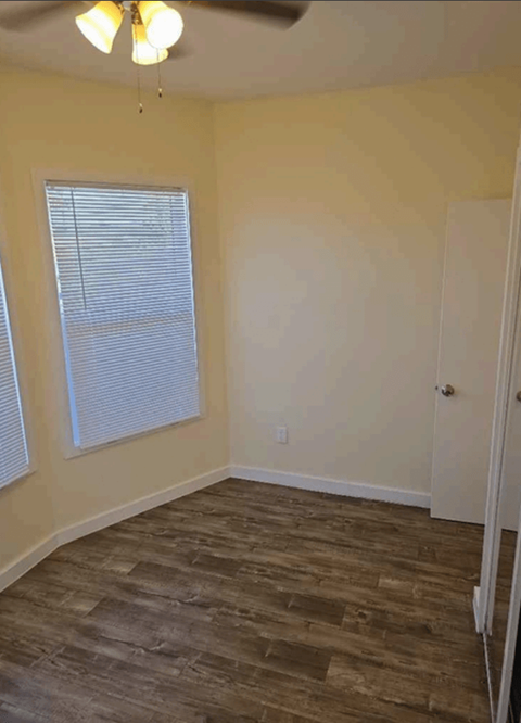 A room with a ceiling fan and a window with blinds.