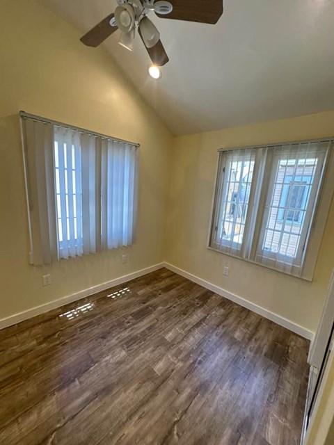 A room with a ceiling fan and wooden flooring.