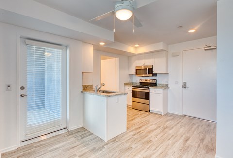a renovated kitchen with white cabinets and a door to the living room