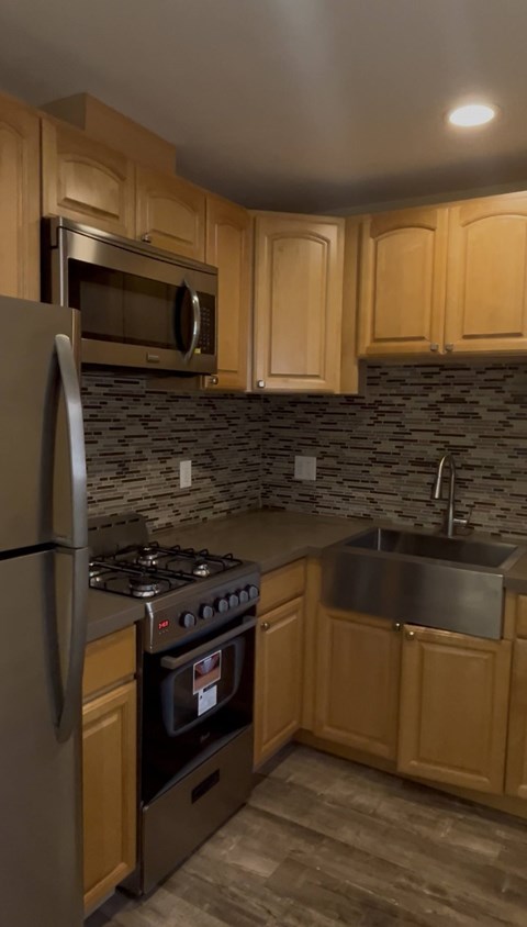 A kitchen with wooden cabinets and a black stone backsplash.