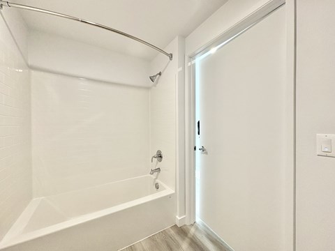 A white bathroom with a tub and a door.