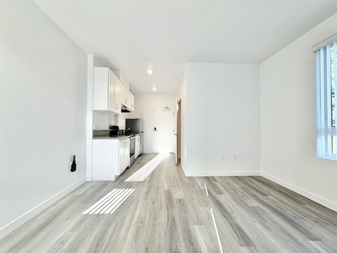 A spacious kitchen with white cabinets and a grey floor.