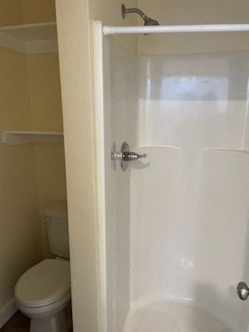 A white toilet sits next to a white shower door.
