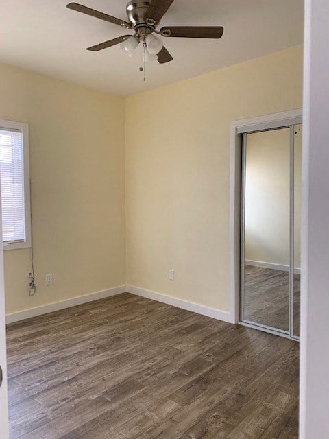 A room with a ceiling fan and wooden flooring.