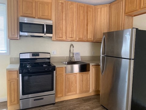 A kitchen with wooden cabinets and a stainless steel refrigerator.