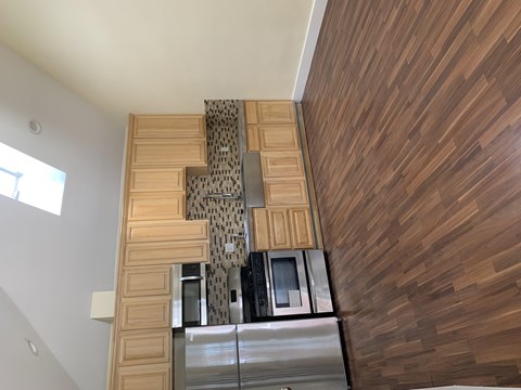 A kitchen with wooden cabinets and a stainless steel refrigerator.