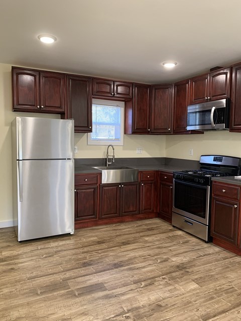 A kitchen with wooden cabinets and a stainless steel refrigerator.