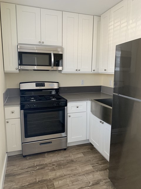 A kitchen with white cabinets and a black refrigerator.
