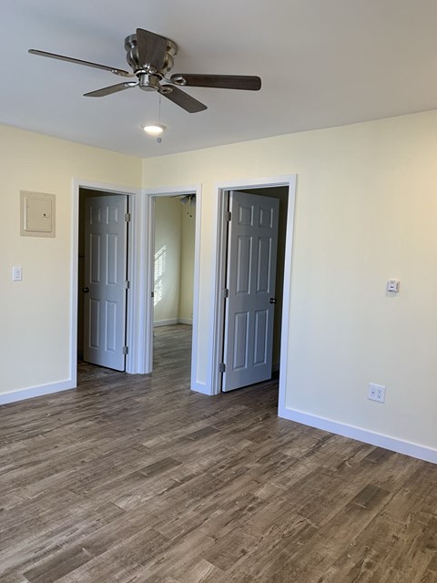 A room with a ceiling fan and two doors.