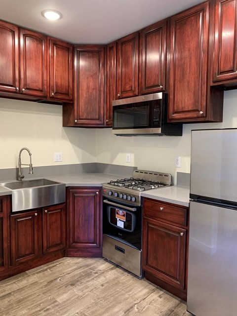 A kitchen with wooden cabinets and a stainless steel refrigerator.