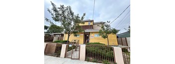 A yellow house with a brown gate in front.