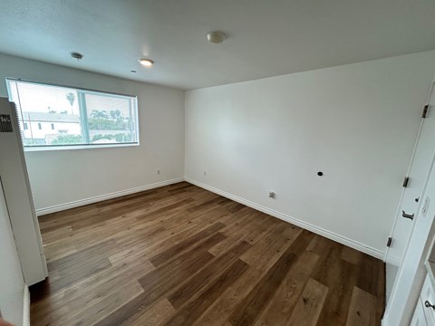 A room with wooden flooring and white walls.