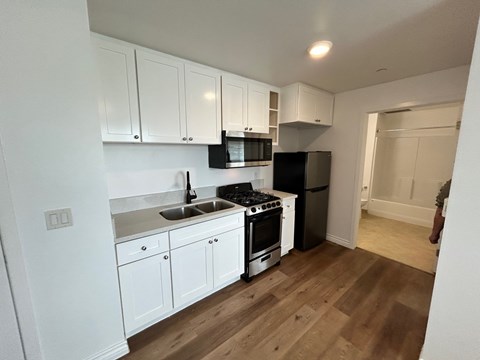 A kitchen with white cabinets and a black refrigerator.