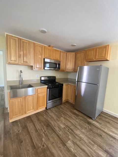 A kitchen with wooden cabinets and a stainless steel refrigerator.