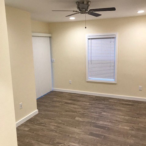 A room with a ceiling fan and a window with blinds.