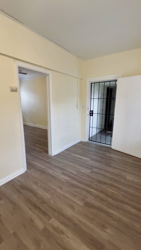 A room with wooden flooring and two doors, one of which is open.