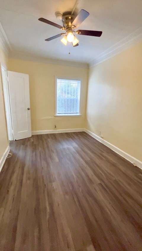 A room with a ceiling fan and wooden flooring.
