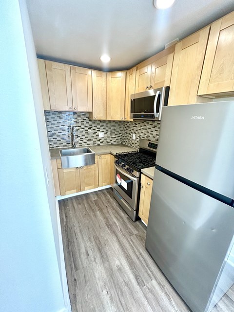 A kitchen with a stainless steel refrigerator and wooden cabinets.