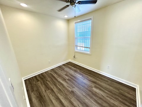A room with a ceiling fan and a window with blinds.