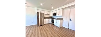 A kitchen with a refrigerator, oven, microwave, and cabinets.