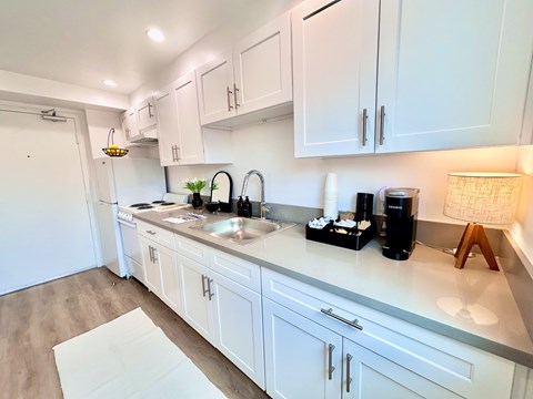 A kitchen with white cabinets and a light wood floor.