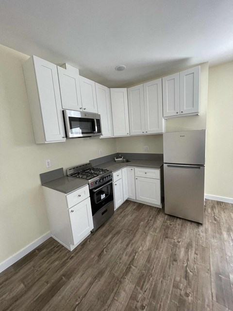 A kitchen with white cabinets and a stainless steel refrigerator.