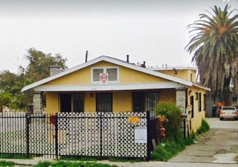 A yellow house with a black and white fence.
