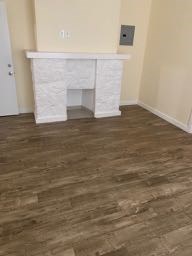 A white fireplace in a room with wooden flooring.