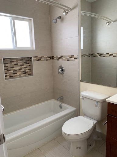 A white toilet sits next to a bathtub in a bathroom.