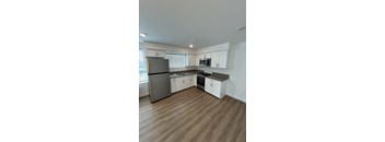 A kitchen with white cabinets and a wooden floor.