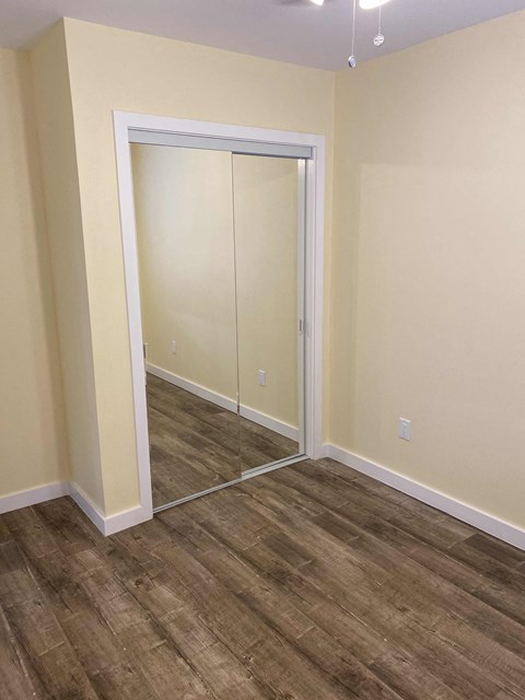 a bedroom with a closet and a hard wood floor
