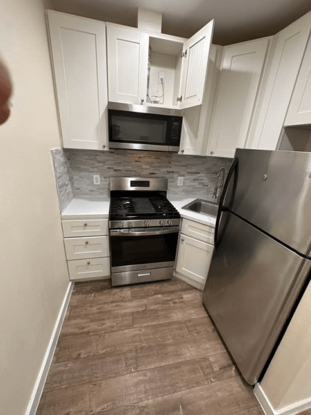 A kitchen with a refrigerator, oven, and microwave.