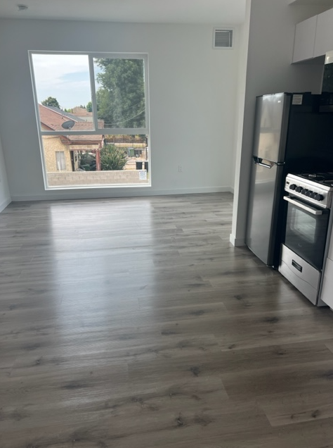 A kitchen with a black fridge and stove next to a window.
