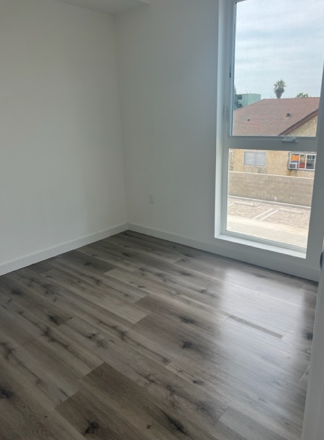 an empty room with a large window and wooden floors
