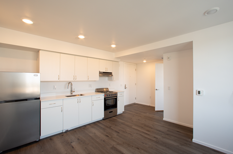 A kitchen with white cabinets and a stainless steel refrigerator.