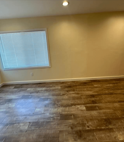 an empty living room with wood floors and a window