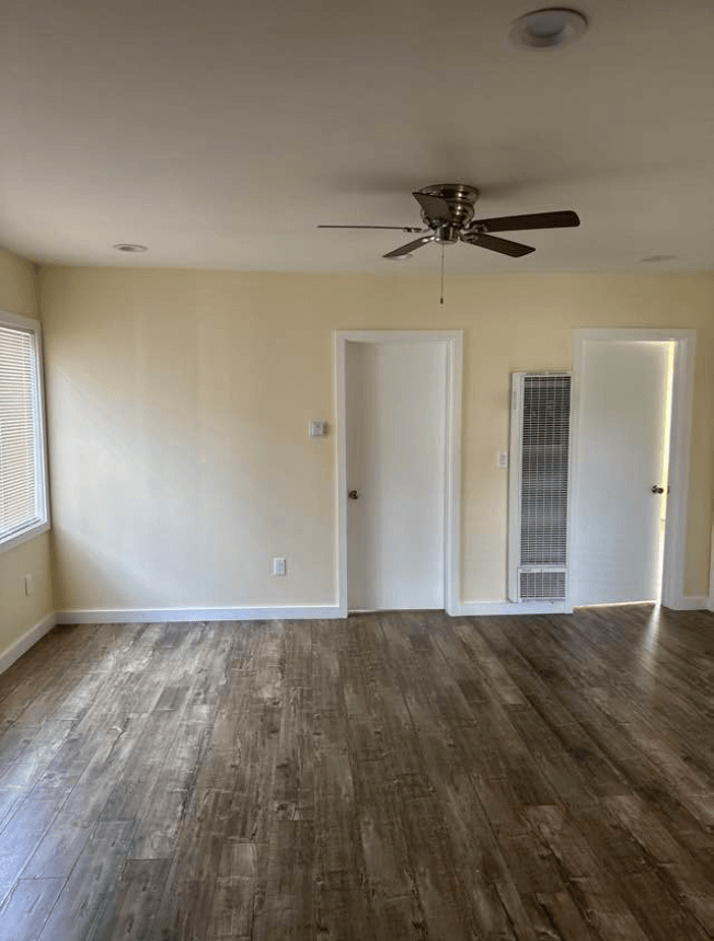 an empty living room with wood floors and a ceiling fan
