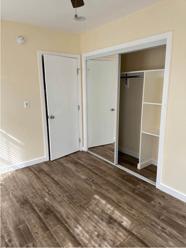 a bedroom with a closet and a hard wood floor