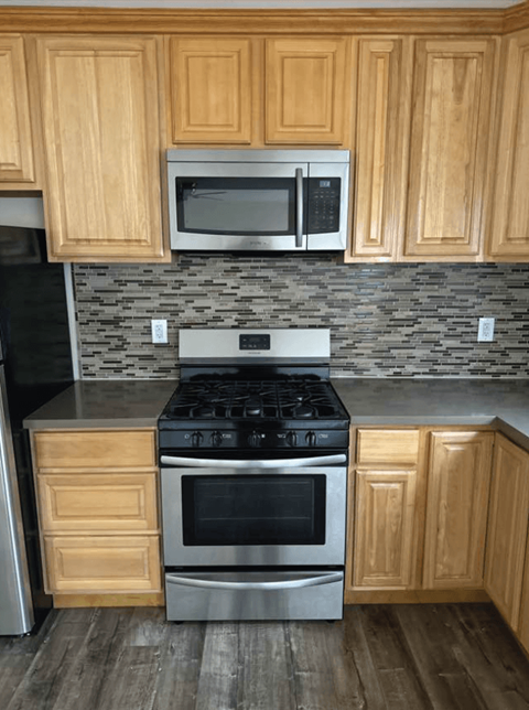 A kitchen with wooden cabinets and a stainless steel oven.