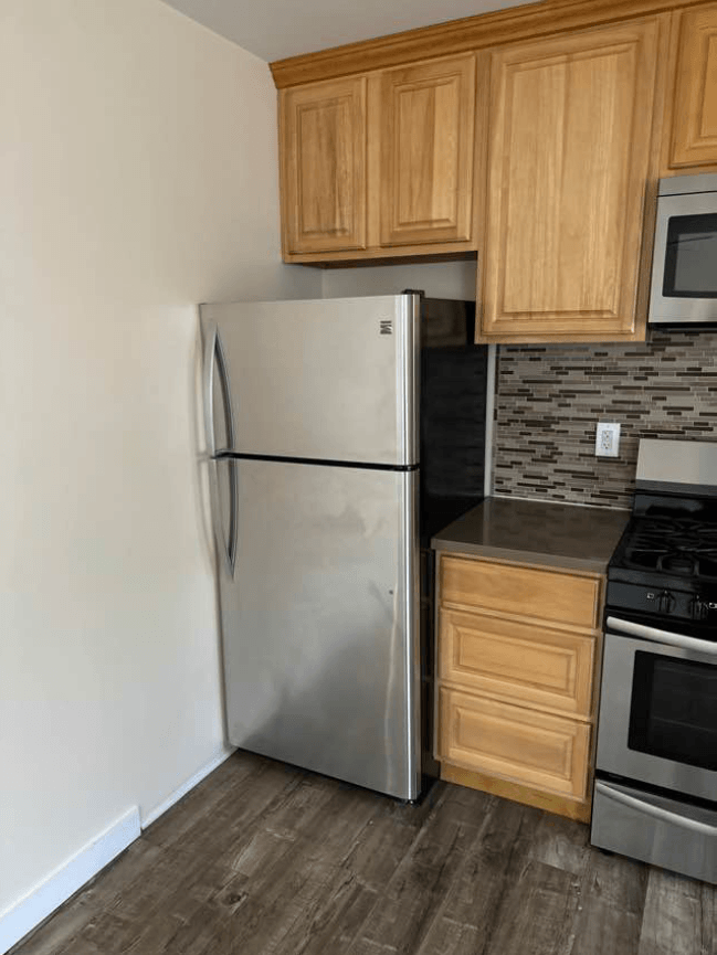 a kitchen with a stainless steel refrigerator and wooden cabinets