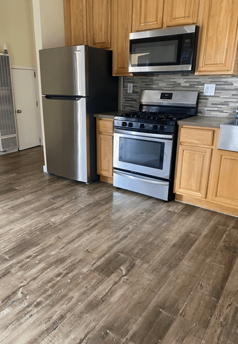 A kitchen with a stainless steel refrigerator, microwave, and oven.