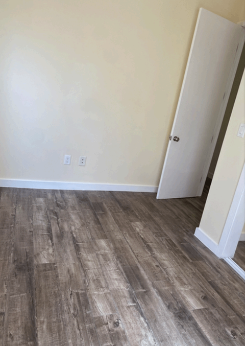 a room with wood flooring and white walls and a door